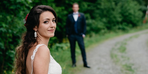 Hochzeitsfotos - Art des Shootings: Hochzeits Shooting - Chiemsee - Braut mit Bräutigam im Hintergrund auf der Maierl-Alm in Kirchberg. WE WILL WEDDINGS | Hochzeitsfotografin Tirol / Wien - WE WILL WEDDINGS