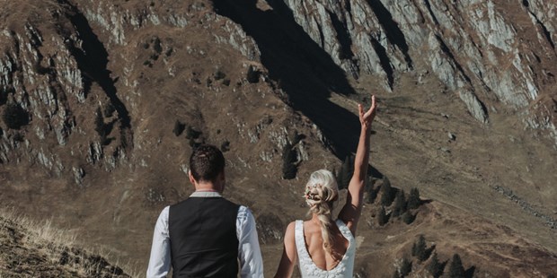 Hochzeitsfotos - Art des Shootings: Prewedding Shooting - Zell am See - Braut wirft Brautstrauß in die Luft bei dem Paarshooting in den Kitzbüheler Alpen - Sophia Eerden