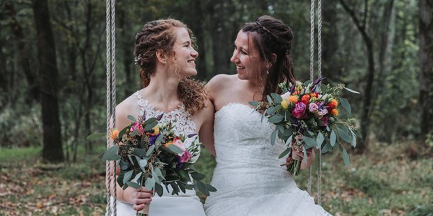 Hochzeitsfotos - Telfs - Brautpaar sitzt auf einer Schaukel und lacht.  - Sophia Eerden
