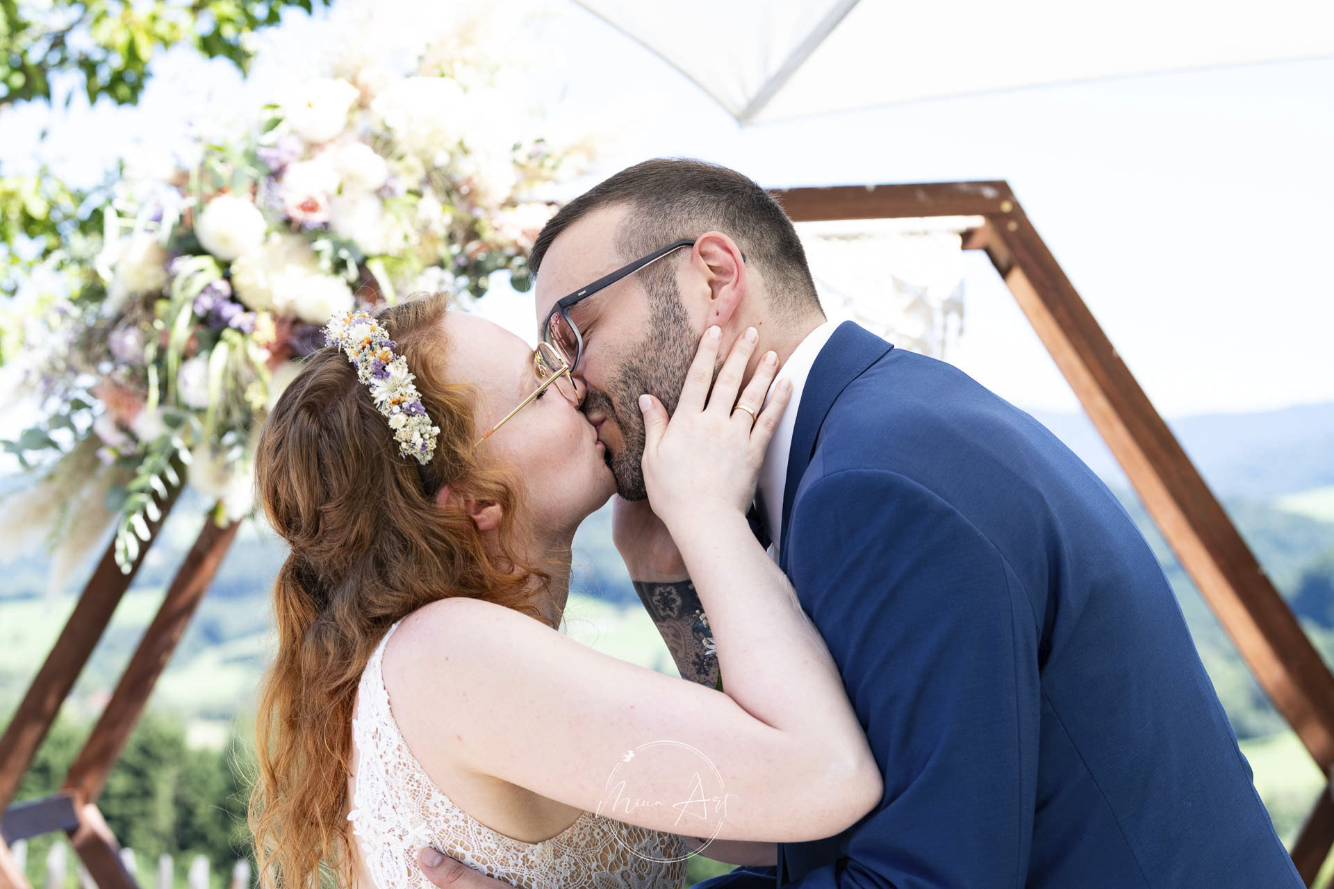 Hochzeitsfotograf - Die Standesamtliche Hochzeit des Brautpaares wurde mit dem ersten Kuss besiegelt - dahinter toller Fernblick ins Grüne, über Almwiesen und Kühe. Das herzliche Paar war romantisch und etwas nerdy verspielt. - Mina Art - Marina Halmenschlager