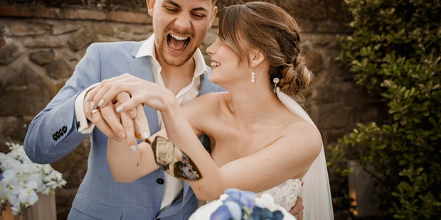 Hochzeitsfotos - Kerpen (Rhein-Erft-Kreis) - Braut hat die Hand oben beim Anschneiden der Hochzeitstorte - abcweddingstories