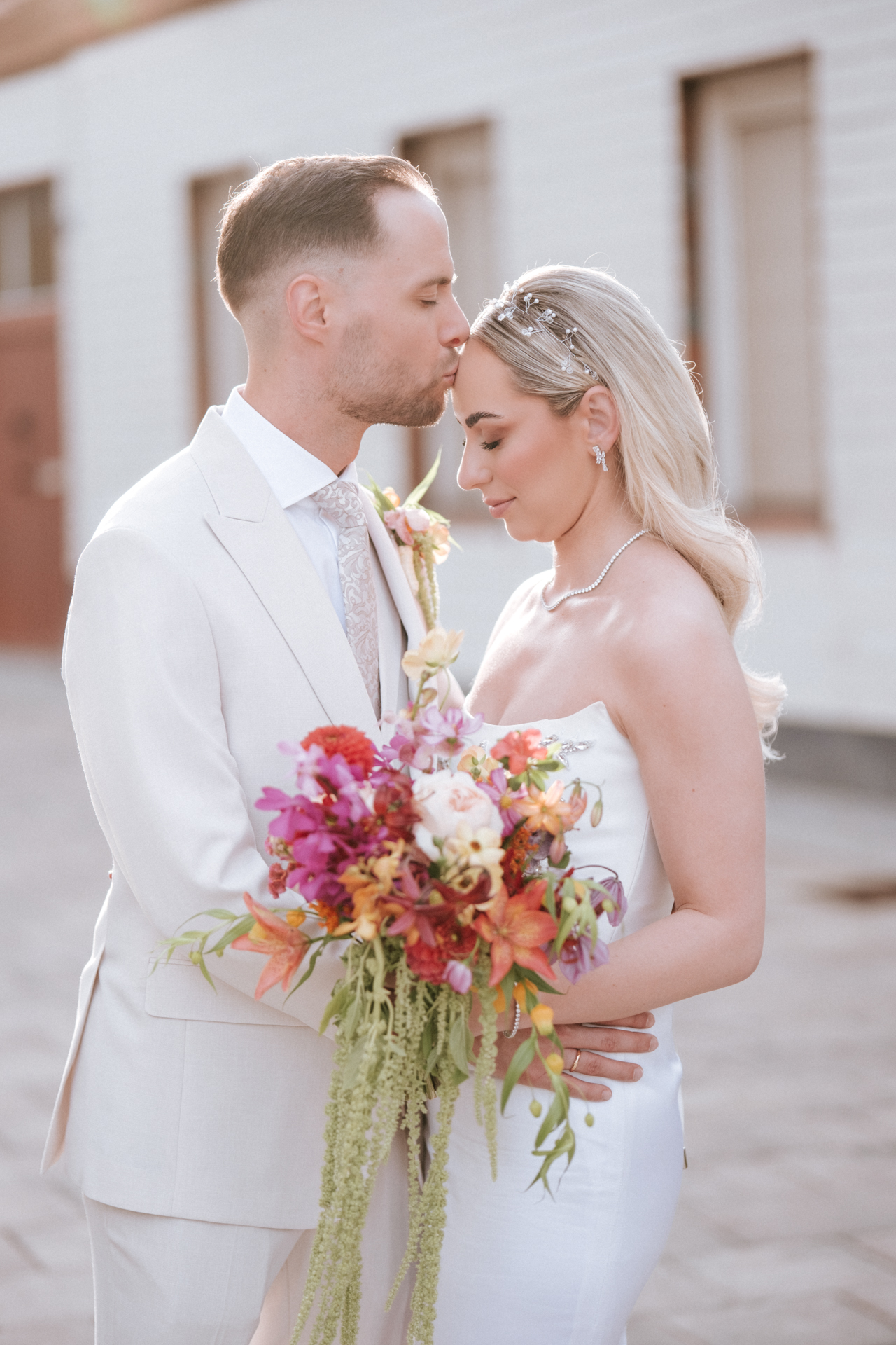 Hochzeitsfotograf: Bräutigam küsst seine Braut auf die Stirn vor dem Alten Rathaus Wiener Neudorf - Pengoo Weddings