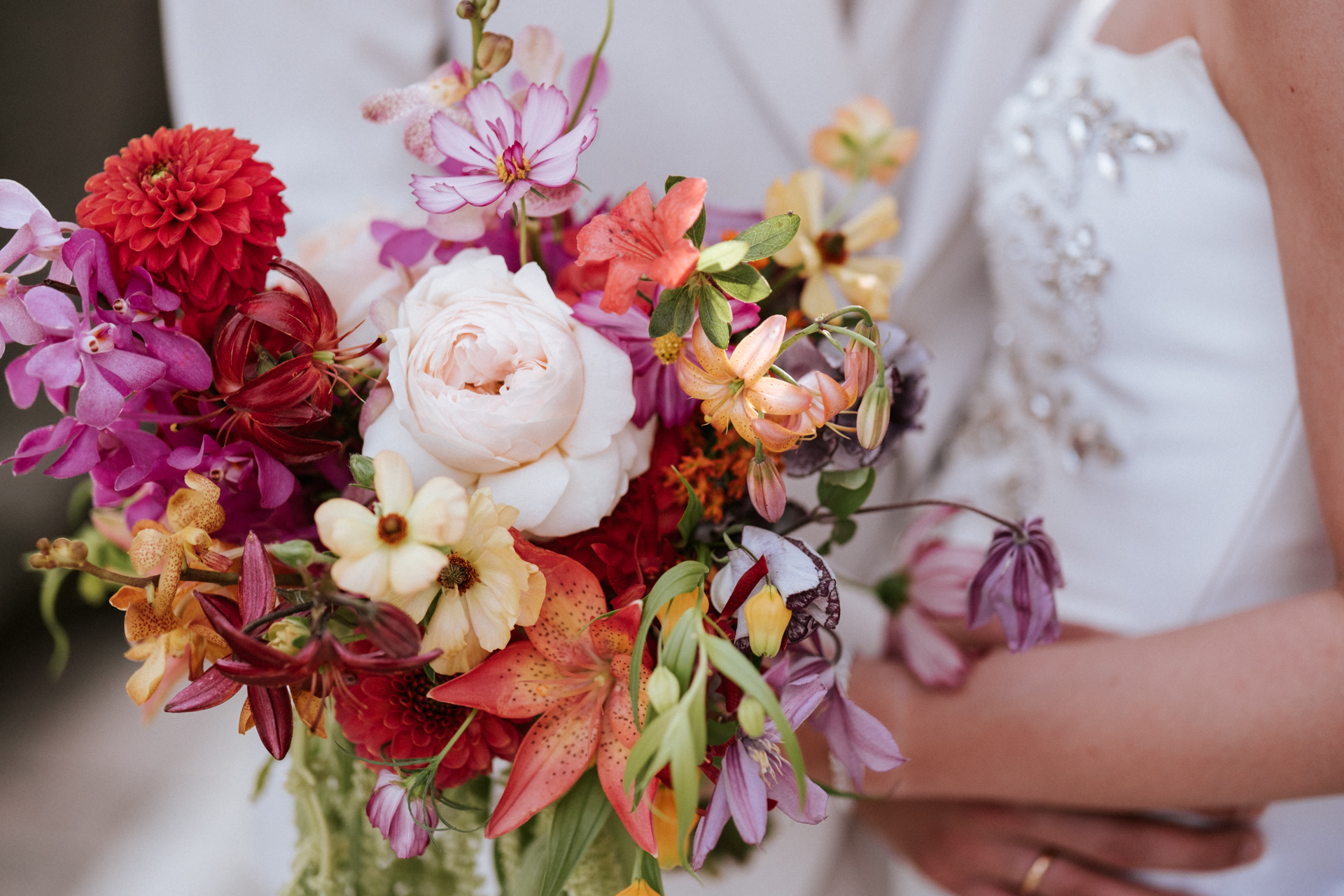 Hochzeitsfotograf: Braut hält bunten Brautstrauß mit Dahlien, Rosen und Orchideen bei einer Hochzeit im Alten Rathaus in Wiener Neudorf - Pengoo Weddings