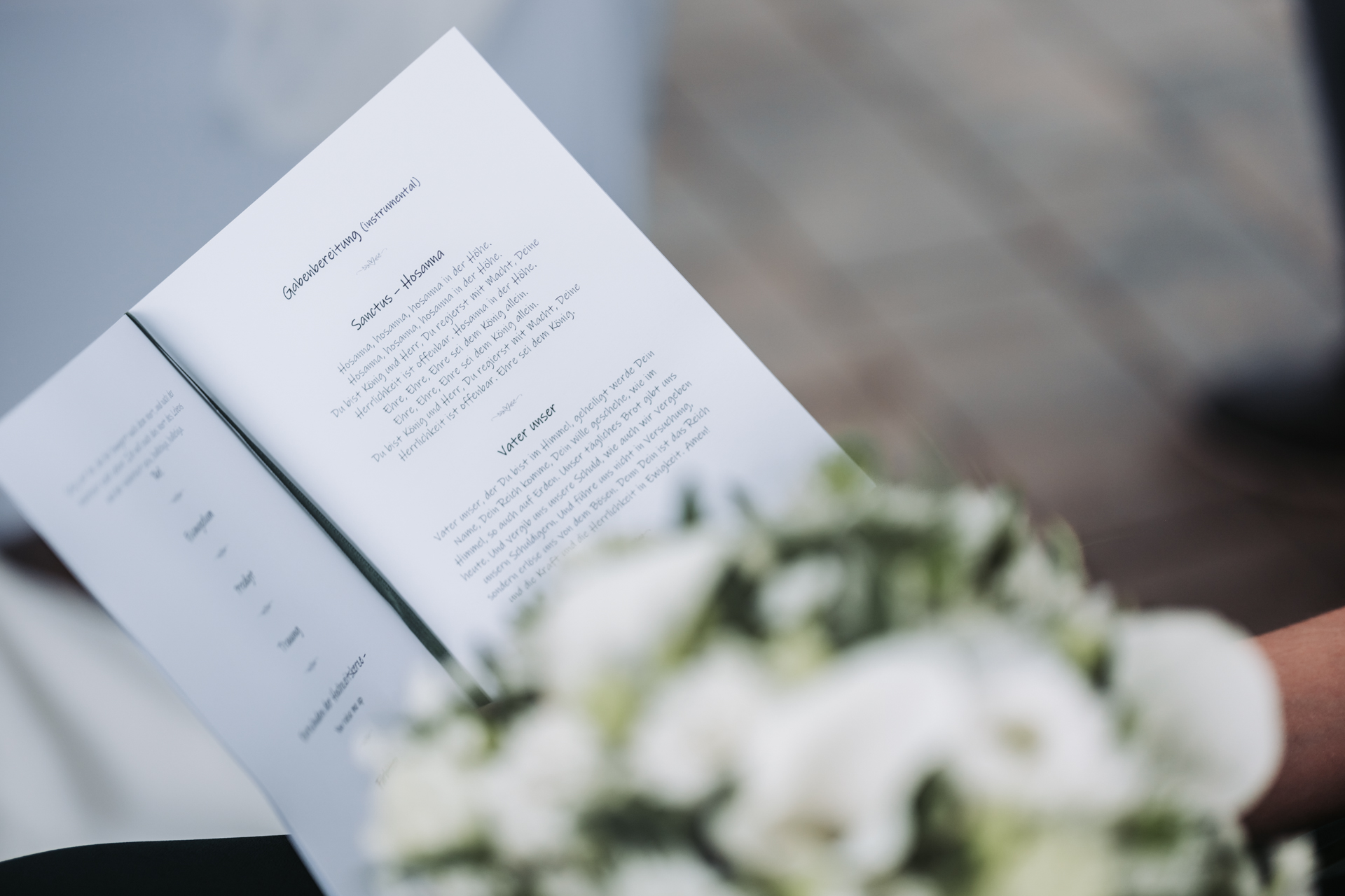 Hochzeitsfotograf: Aufgeschlagene Liedertexte neben weißem Brautstrauß bei einer Hochzeit am Kahlenberg in Wien - Pengoo Weddings