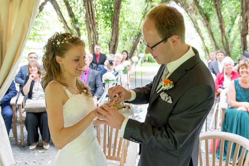 Hochzeitsfotos - Berufsfotograf - Velten - Ringanstecken im Weidendom Schlepzig bei einer Hochzeit im Spreewald. - rotschwarz design
