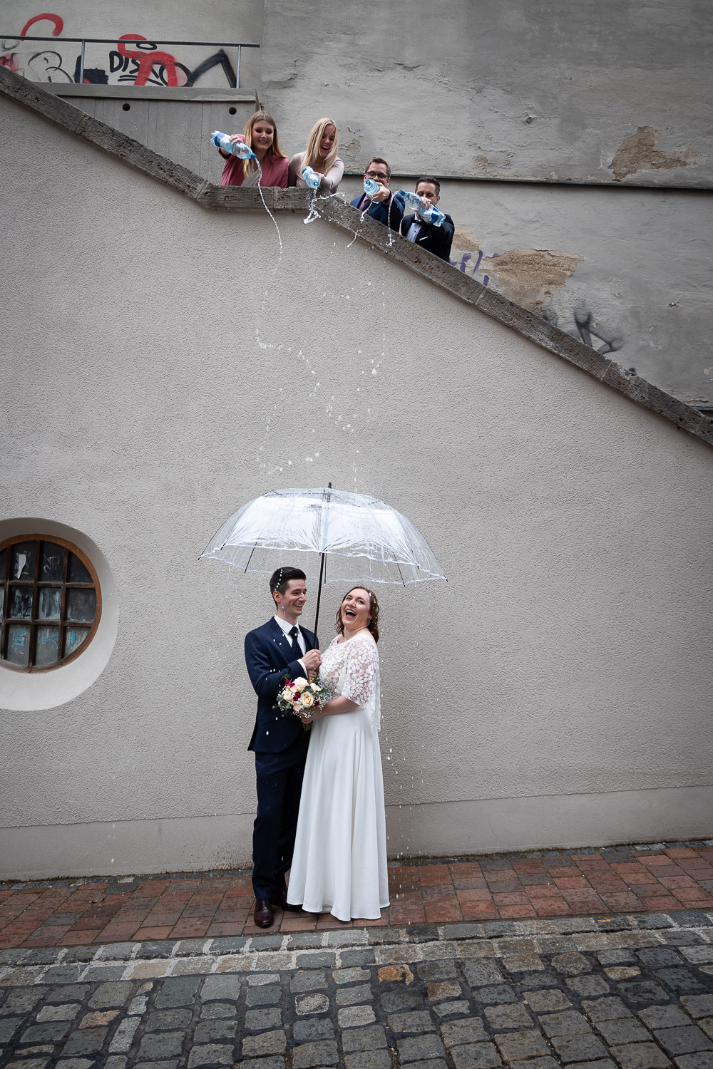 Hochzeitsfotograf: Romantisches Paarshooting im "Regen": Das Brautpaar steht gemeinsam unter einem weißen Regenschirm. - Zammgfasst