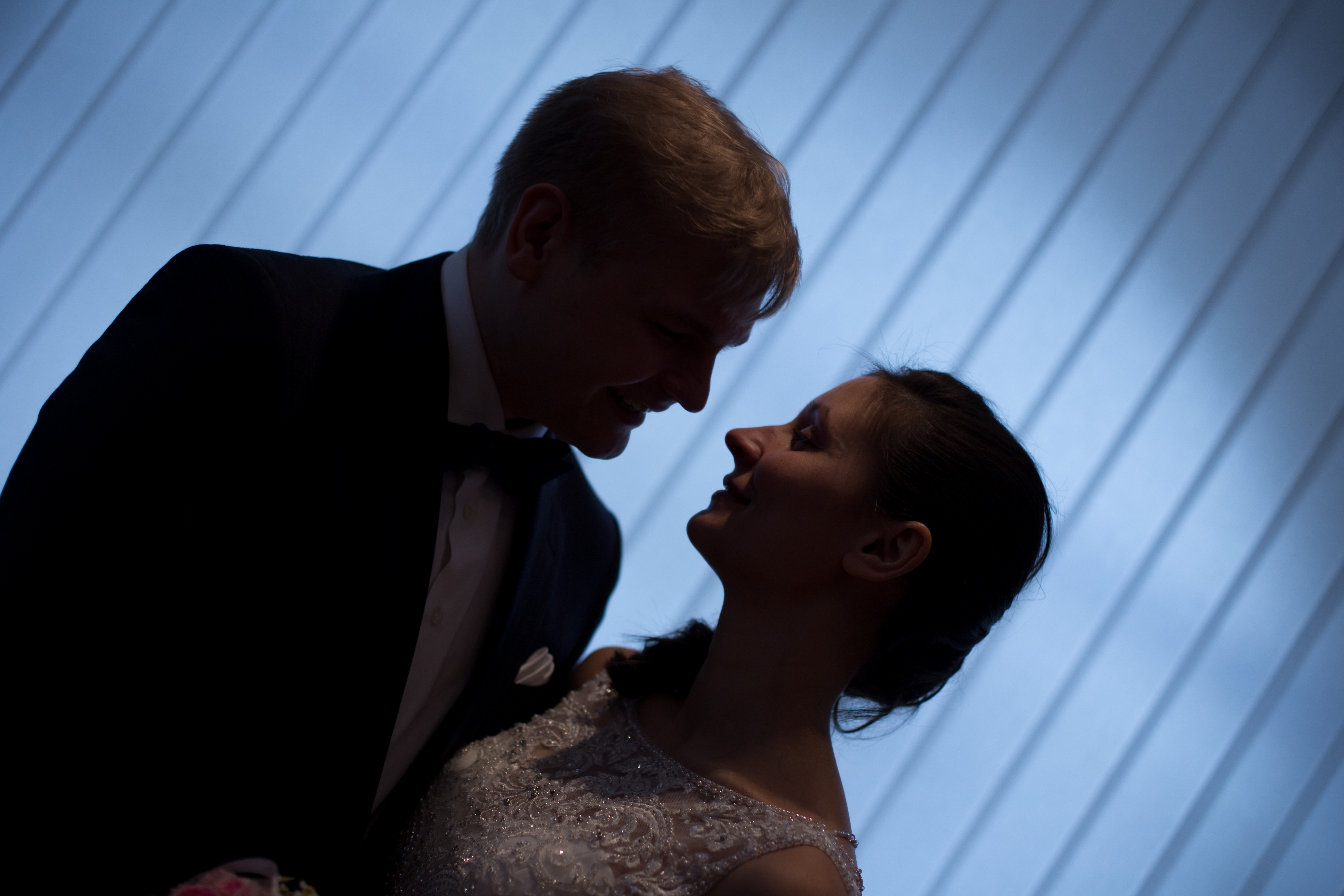 Hochzeitsfotograf: Stimmungsvolles Hochzeitsporträt eines Brautpaares vor einer hellen Wand mit geometrischen Linien.   - Zammgfasst
