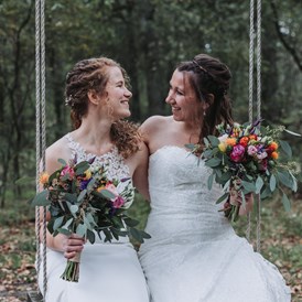 Hochzeitsfotograf: Brautpaar sitzt auf einer Schaukel und lacht.  - Sophia Eerden
